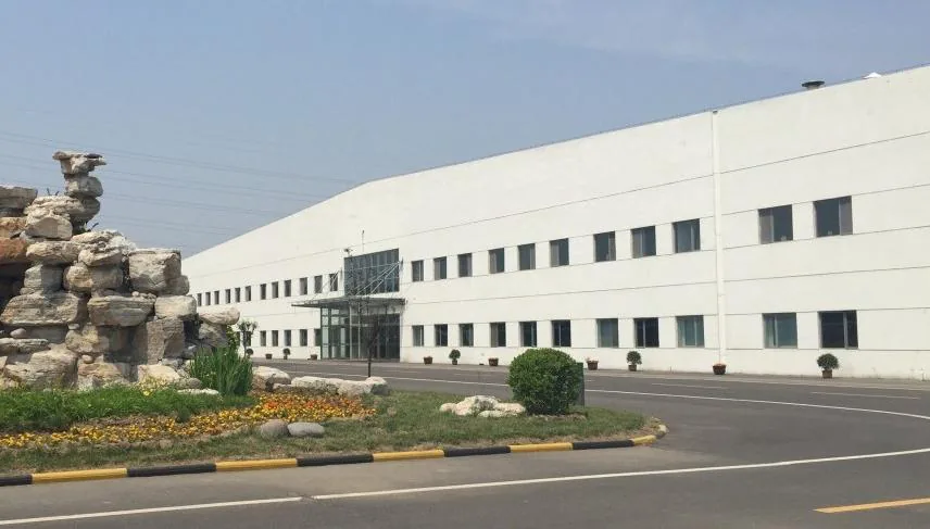 Exterior of a large single-storey manufacturing plant with landscaped grounds.